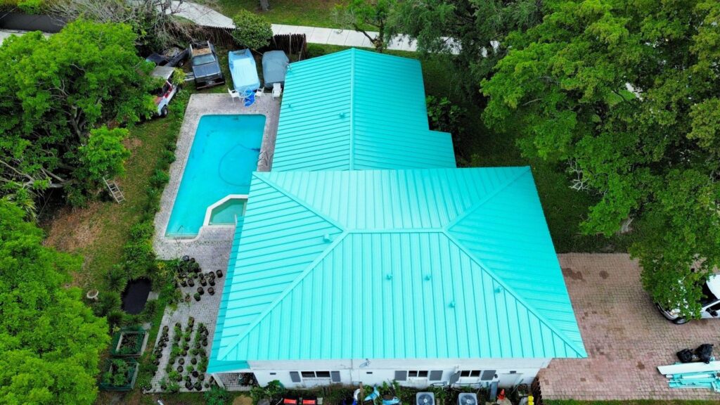 Roofing contractor installing standing seam metal roofing panels on commercial building